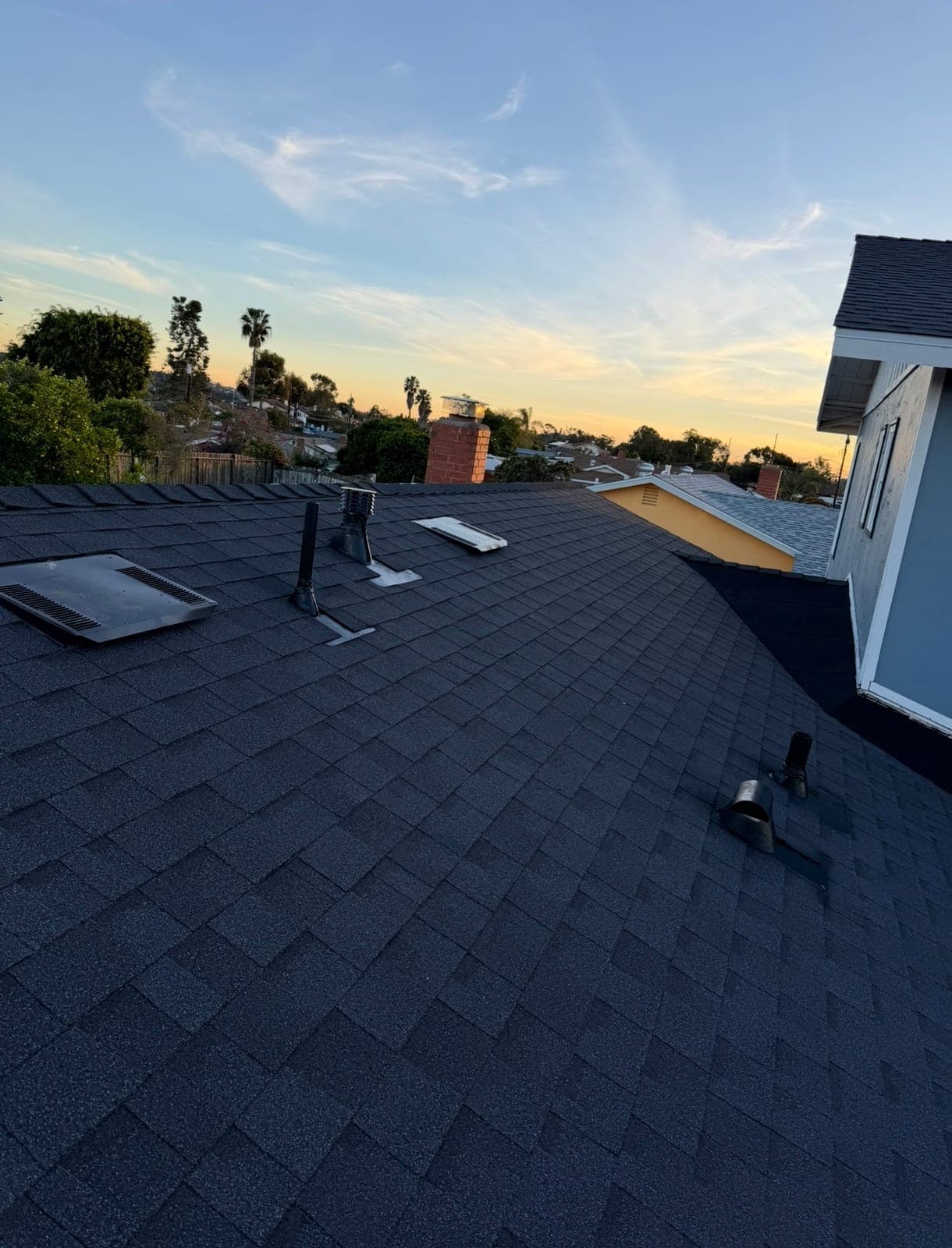 New charcoal shingles and fresh flashing details at dusk