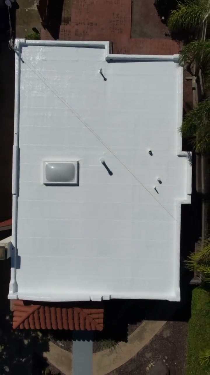 Flat roof finished in a bright white protective coating, seen from above